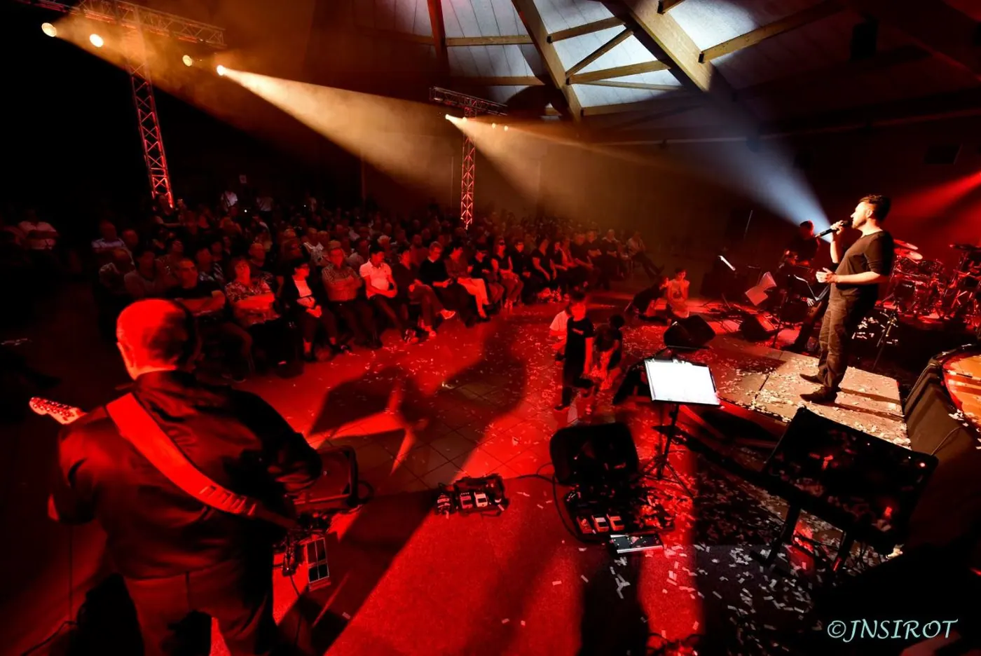 Vue de la scène depuis les musiciens, public en contrebas, lumière orangée